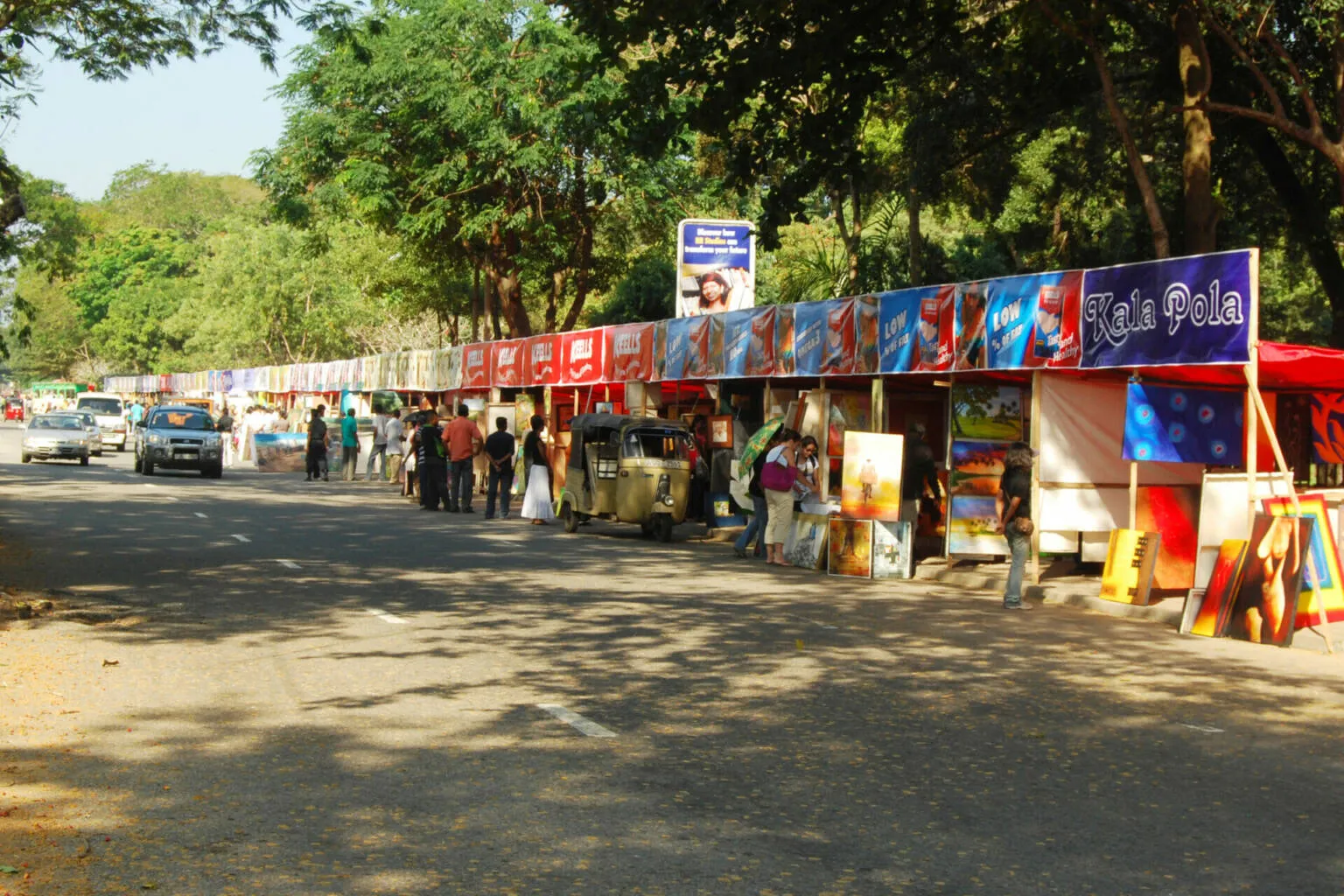 A bustling street lined with various vendors showcasing their colorful goods and paints attracting passersby.